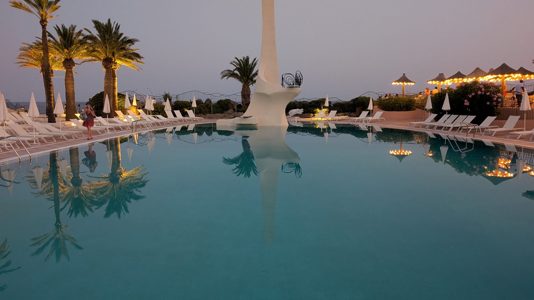 Summer Club pool at dusk, diving tower reflected