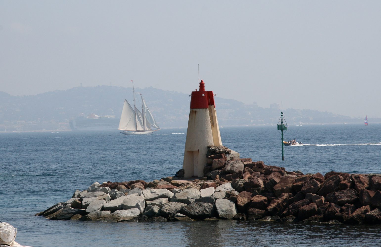 Port La Galère jetty light with a sailboat and the Esterel shore