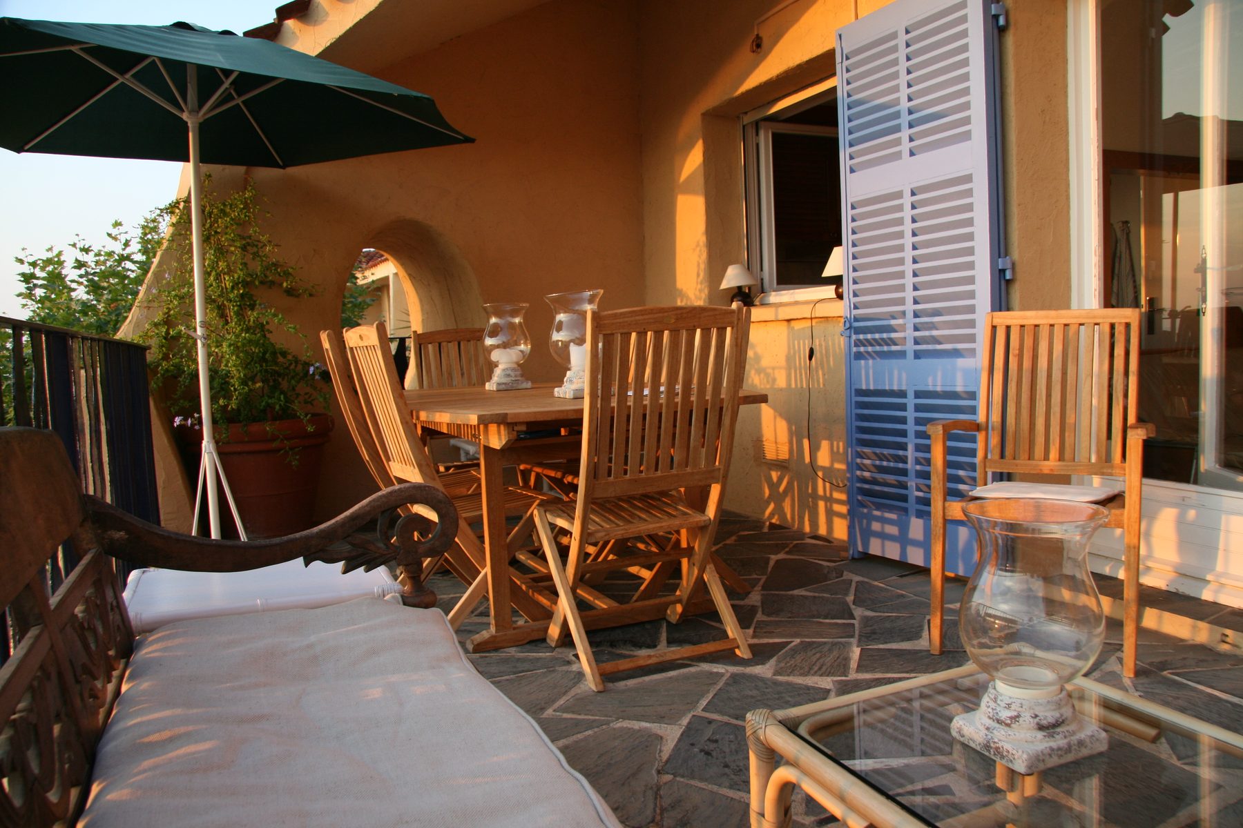 Terrace table and blue shutters in morning light